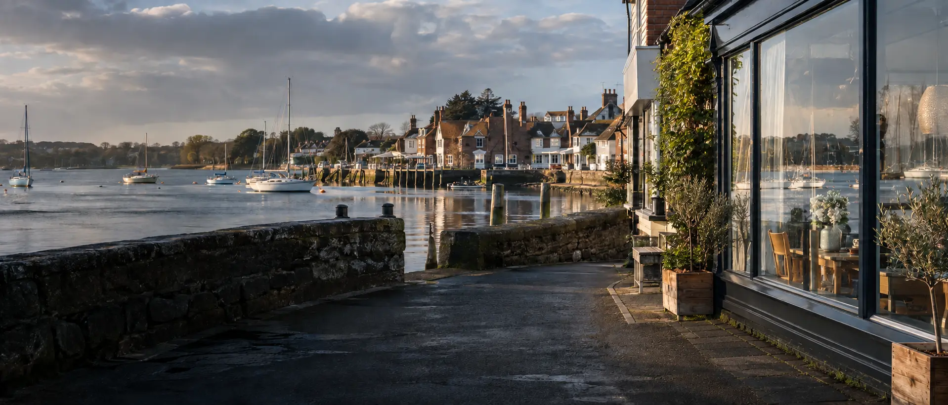 Illustrative harbourfront shop glazing and moored boats in an Emsworth-style coastal setting